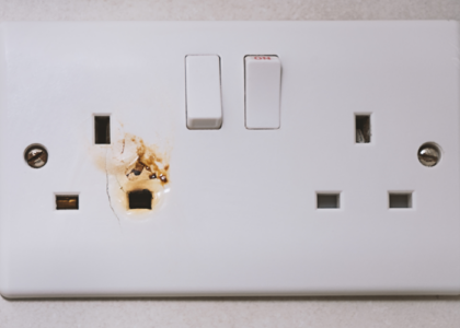Standard UK double outlet socket with visible burn marks and signs of electrical arcing