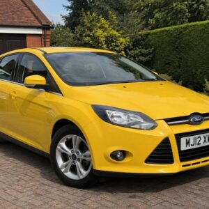 Yellow Ford car on a residential driveway representing a used car listing on Xcat Motors