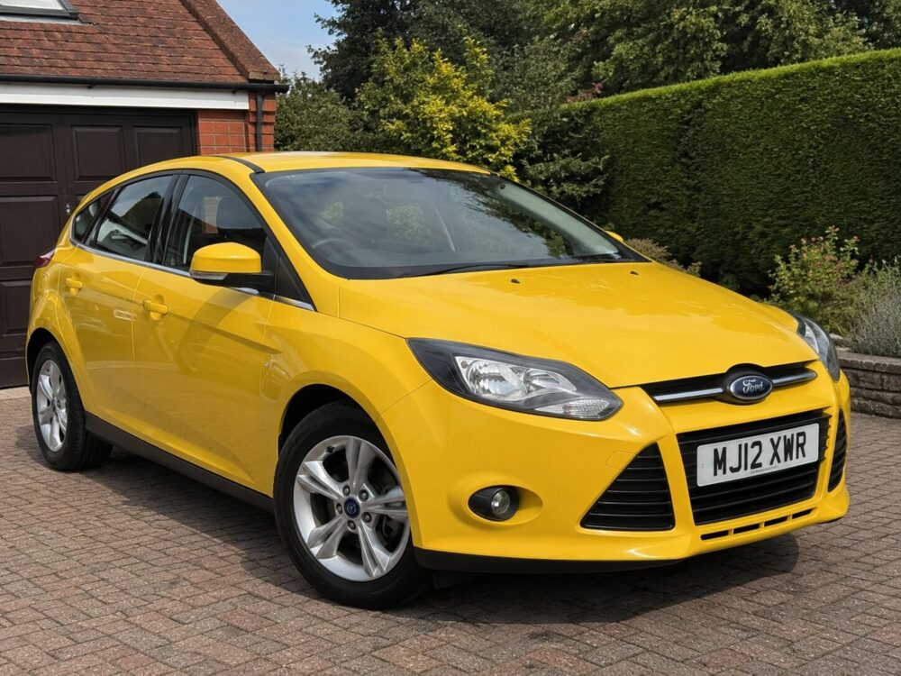 Yellow Ford car on a residential driveway representing a used car listing on Xcat Motors